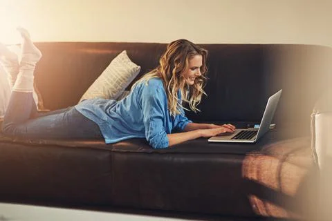 Who needs a desk when youre a blogger. a relaxed young woman using a laptop on Stock Photos