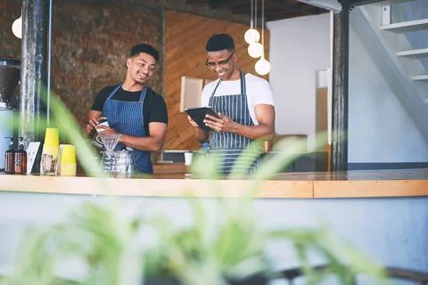 Who needs paper to run a profitable business. two young men using a digital Stock Photos