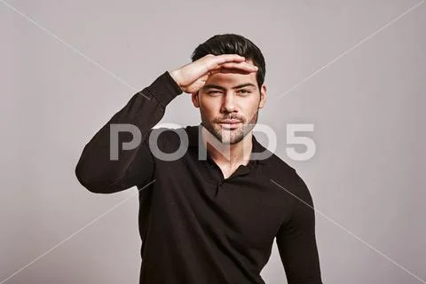 Who is there? Stylish dark-haired man in brown jumper is squinting, trying to Stock Photos