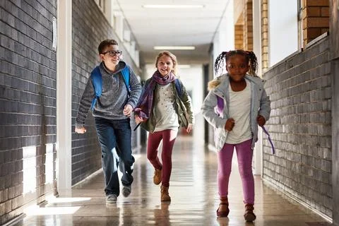 Who will get to class first. elementary school kids running in the corridor at Stock Photos