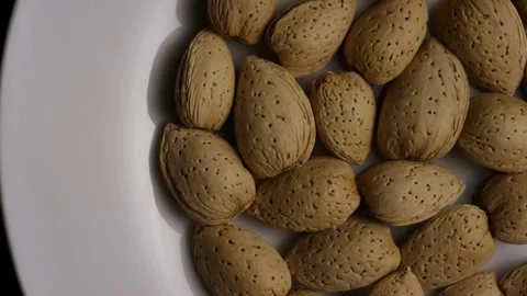 Whole almonds in shells arranged on a white plate Stock Footage 327829245