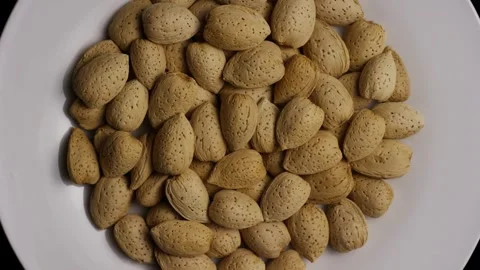 Whole almonds in shells rotating on a white plate Stock Footage 328135855