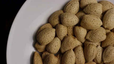 Whole almonds in shells rotating on white plate Stock Footage 328135963
