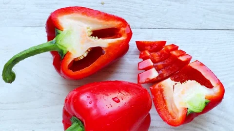 A whole and chopped red pepper lies on a wooden table Stock Footage 236542136