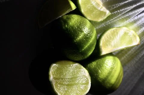 Whole and Cut Limes in Dramatic Low-Key Light Macro Stock Photos