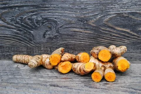 Whole and cut tumeric root on a rustic wooden background Stock Photos