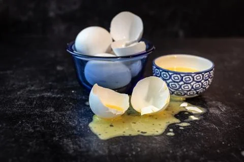 Whole and eggshell halfs spiled messy scrammbled egg yolks Stock Photos