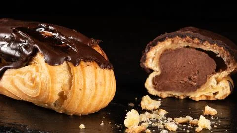 Whole and halved eclair on dark background, close-up dessert photography Stock Photos