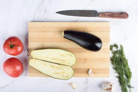 Whole and halved eggplants on a cutting board. Stock Photos