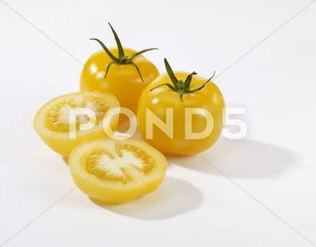 Whole and halved yellow tomatoes Stock Photos