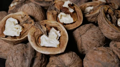 Whole and peeled walnuts rotate around an axis on a plate. Close-up. Stock Footage 297780893