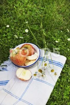 A whole apple and apple wedges in an old enamel bowl on a linen cloth in a Stock Photos