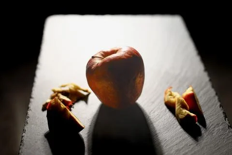 Whole apple dramatically lit from behind, surrounded by cut peel pieces Foto stock