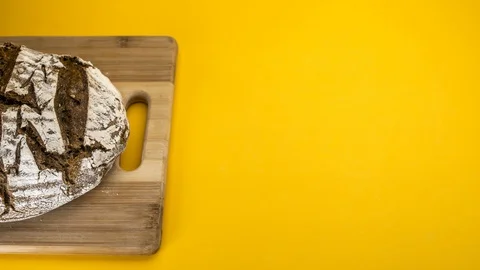 Whole bread on a cutting board, stop motion animation on yellow background 4k Stock Footage 129030244