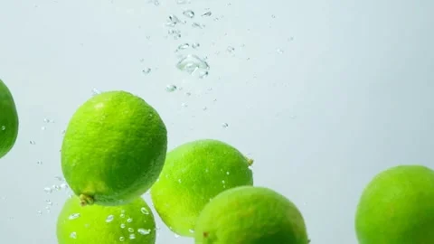 Whole fresh lime fruit submerged in water, lots of water bubbles, slow motion Stock Footage 308077230