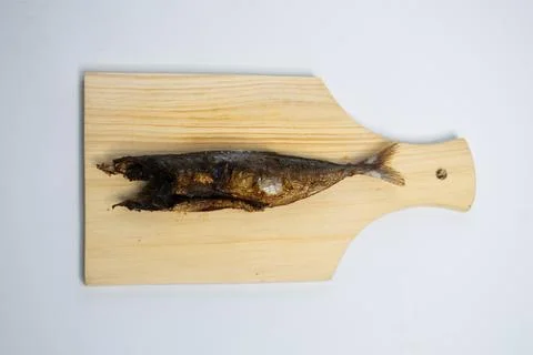 Whole fried fish placed on a light wooden board, ready to be served. Stock Photos