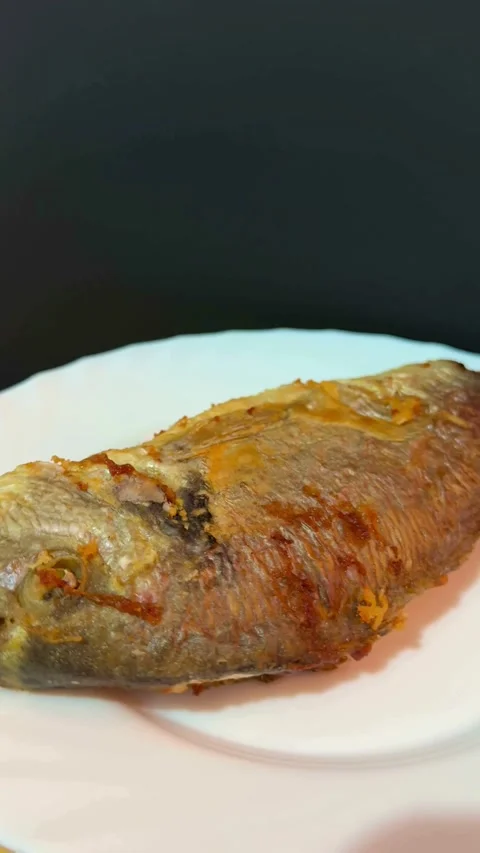 Whole fried fish served on a white round plate Video stock 331974794
