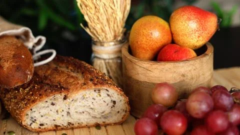 Whole-grain bread, fresh fruit, wheat bundle, and wooden textures evoke simple Stock Photos