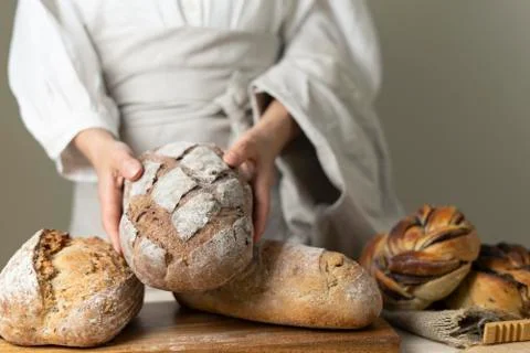 Whole-grain bread put on a kitchen wooden Board with the chef holding a cutting Stock Photos