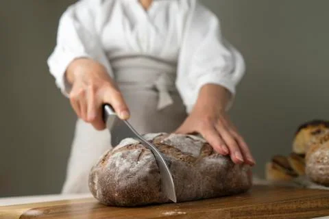 Whole-grain bread put on a kitchen wooden Board with the chef holding a cutting Stock Photos