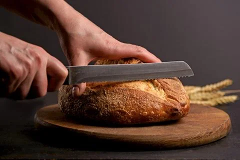 Whole grain bread put on kitchen wood plate with a chef holding knife for cut Stock Photos