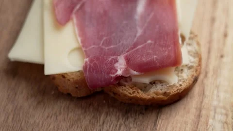 Whole grain bread with slice of Swiss cheese and sliced cured ham Stock Footage 303854140