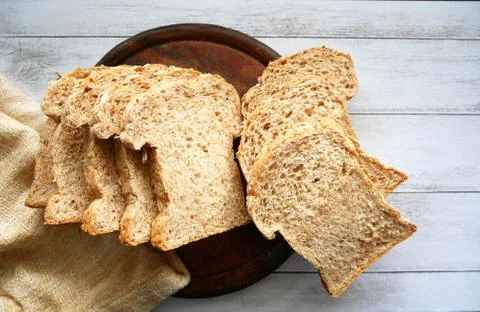 Whole grain bread sliced on white wood background. Stock Photos