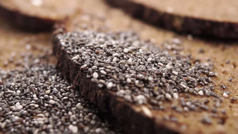 Whole grain bread slices with baked crust and falling chia seeds. Macro Vidéo 163216796