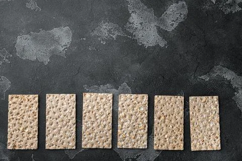 Whole grain crisp bread, on black dark stone table background, top view flat  Stock Photos