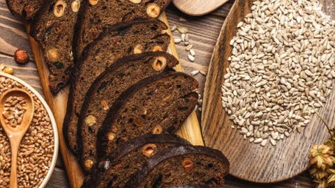Whole grain multigrain bread, whole and sliced, contains seeds isolated on black Stock Footage 101438800