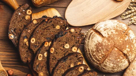 Whole grain multigrain bread, whole and sliced, contains seeds isolated on black Stock Footage 101439712