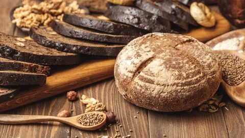 Whole grain multigrain bread, whole and sliced, contains seeds isolated on black Stock Footage 101440929