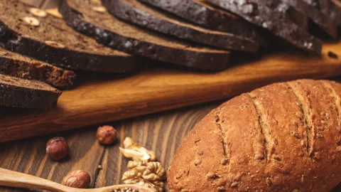 Whole grain multigrain bread, whole and sliced, contains seeds isolated on black Stock Footage 101441363