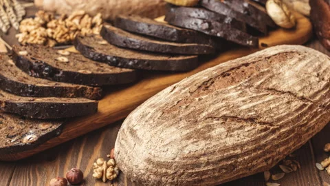 Whole grain multigrain bread, whole and sliced, contains seeds isolated on black Stock Footage 101441569