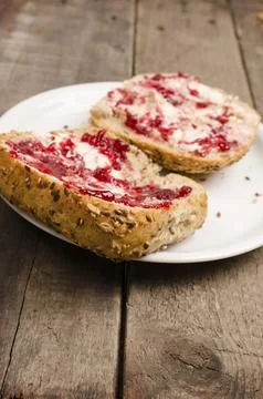 Whole grain rolls with raspberry jam on an old wooden table Stock Photos