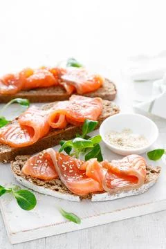 Whole grain rye bread open sandwiches with salted salmon on a white rustic wo Foto stock