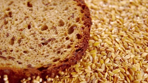 Whole grain rye slice of dark bread in a pile of flaxseeds. Grain fiber healt Stock Footage 166807458