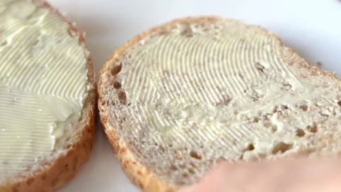 Whole-grain toast bread, buttered, on a white plate with a knife on the side Stock Footage 220292693