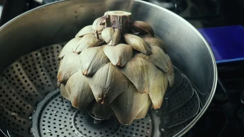 Whole green artichoke steaming inside a metal pot Vídeos de archivo 338159057