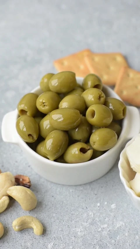 Whole green olives without pits in a bowl as an ingredient for cooking at home.  Stock Footage 336512714