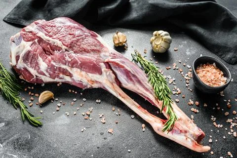Whole lamb leg. Raw organic meat. Black background. Top view Stock Photos