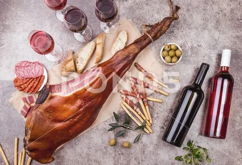 Whole leg HAM JAMON SERRANO and red and rose wine on gray background. Top view Stock Photos