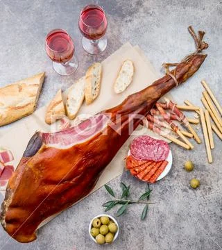 Whole leg HAM JAMON SERRANO and rose wine on gray background. Top view. Flat lay Stock Photos