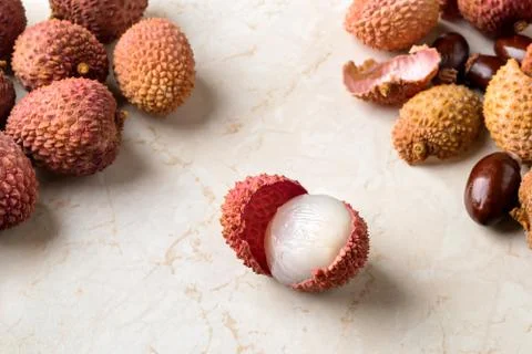 Whole lychee, shells and bones near half peeled lychee fruit on a kitchen table Stock Photos