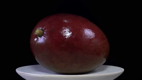 A whole mango fruit on a plate rotates in 4K Stock Footage 140753569