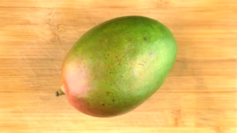 Whole mango fruit rotates back and forth on cutting board. Vidéo 144669928