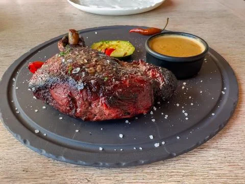Whole Medium Rare beef steak with grilled vegetables on dish Stock Photos