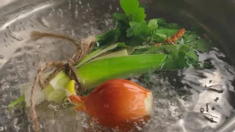 Whole onion falling into a pot of boiling water with herbs. Slow motion Video stock 314625277
