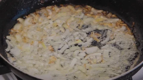 Whole pan view of slices of chopped white onion roasting in oil Stock Footage 102532688