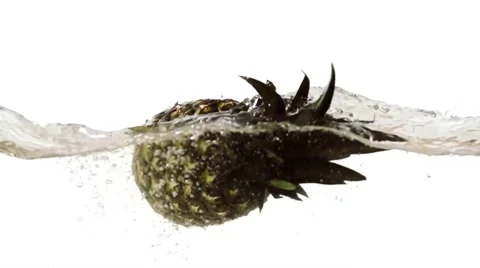 Whole pineapple falling into water on white background slow motion HD video Stock Footage 68458533